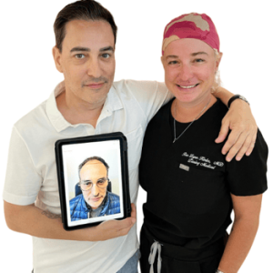 A man and a woman pose together, with the man holding a tablet displaying a close-up photo of another man. The woman, wearing a black shirt with a name tag and a pink surgical cap, stands beside him with a friendly smile. This image highlights a professional interaction, possibly in a medical or aesthetic context, emphasizing the importance of personal care and consultation.
